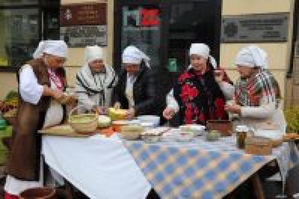 Kobiety w strojach wiejskich z epoki przed muzeum przygotowują potrawy