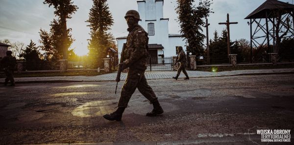 Żołnierz z karabinem idzie ulicą